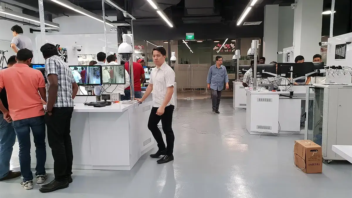 A busy classroom at Inventive Media featuring students and instructors engaged in hands-on CCTV training with professional surveillance equipment