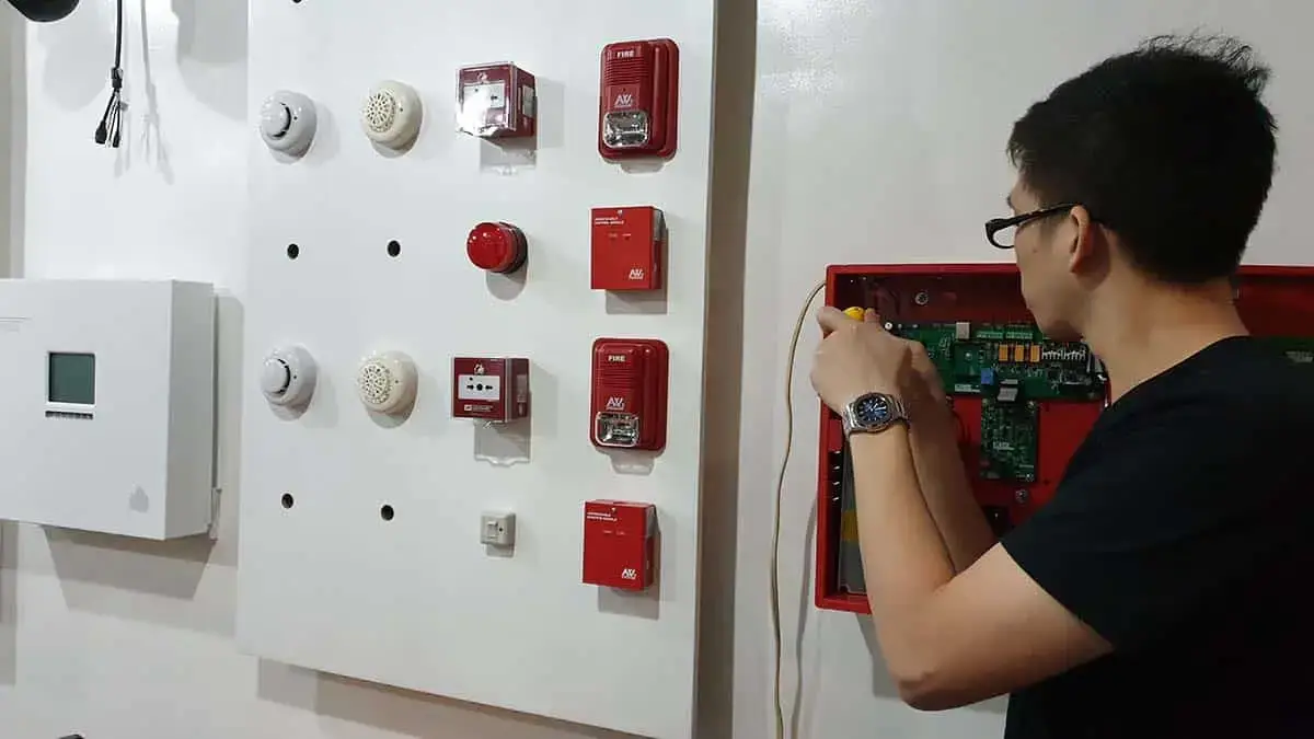 A technical student at a training center in the Philippines practicing the installation and maintenance of fire alarm systems on a technical demonstration board.