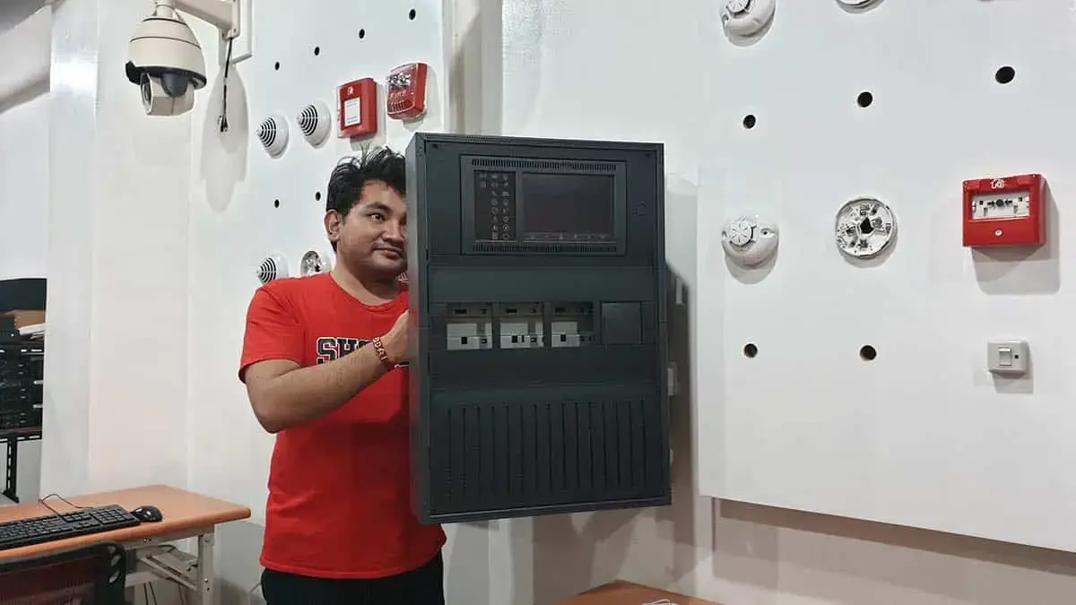 A technical student at a training center in the Philippines practicing the installation and wiring of a Fire Detection and Alarm System (FDAS) control panel.
