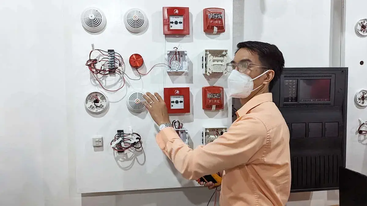 A technician inspecting fire detection and alarm system (FDAS) components during a hands-on training course in the Philippines