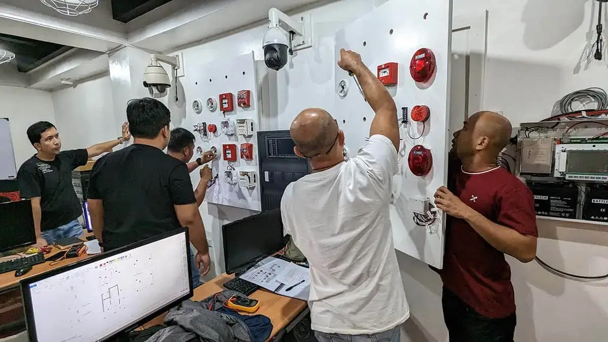 Students working on FDAS control panels during practical training in the Philippines