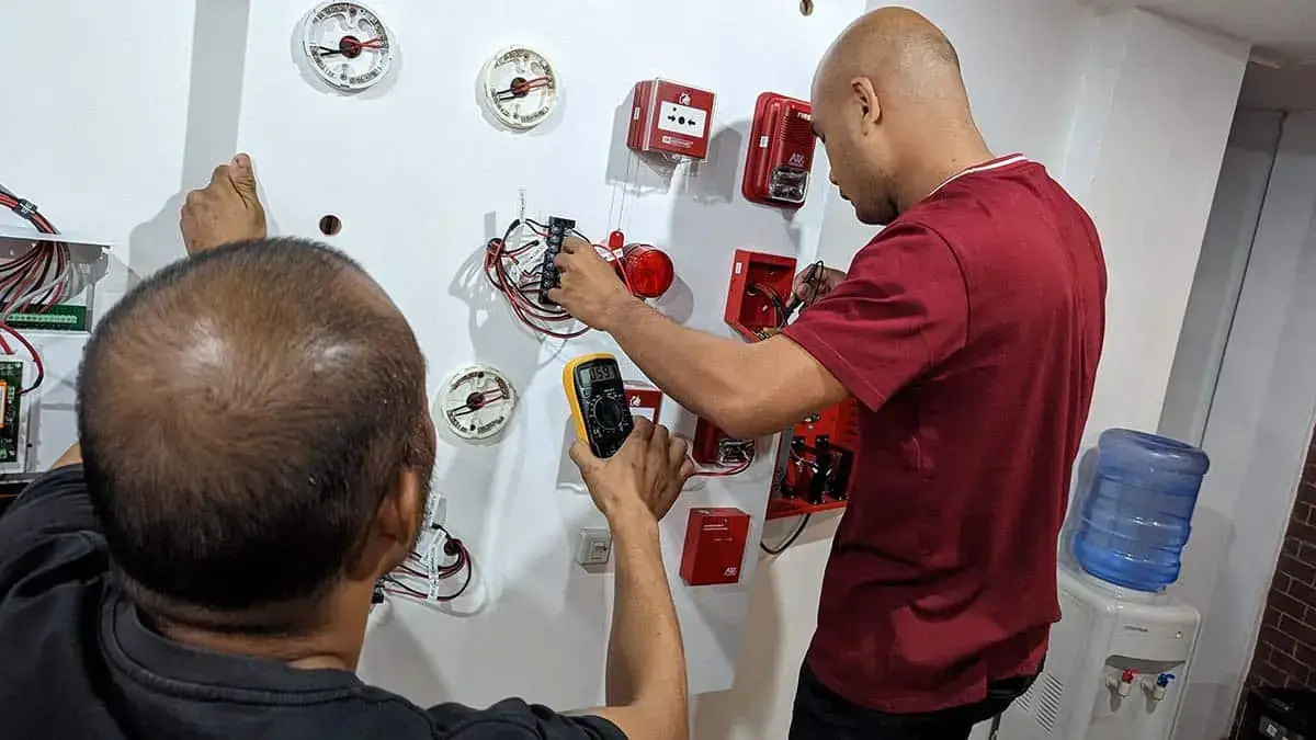Trainees diagnosing and fixing a simulated FDAS system issue during a hands-on workshop